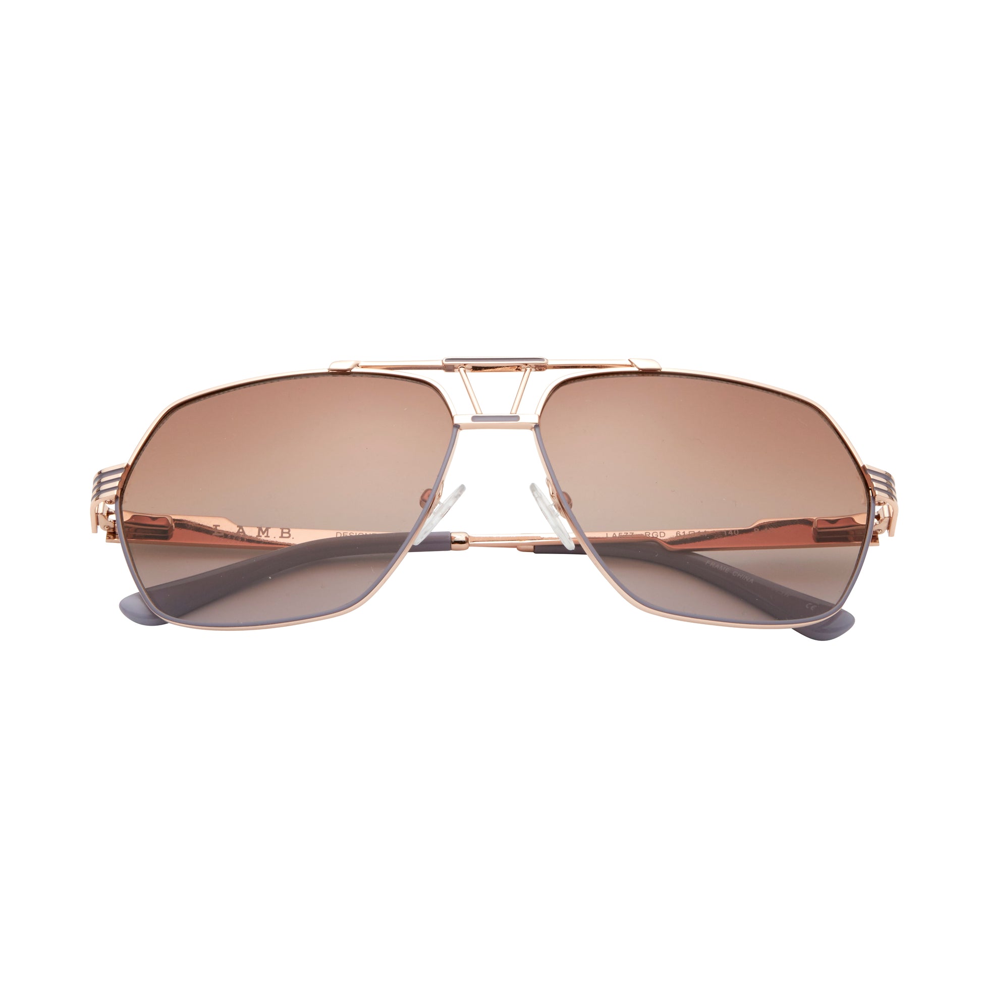 L.A.M.B. LA577 RGD sunglasses with a geometric aviator rose gold metal frame, gradient brown lenses, signature cutout bridge design, and sleek striped temples with grey temple tips. Front view.