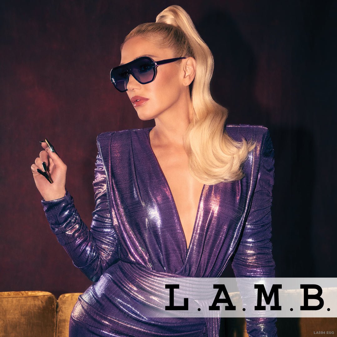 Woman wearing L.A.M.B. LA594 EGG purple shield sunglasses with purple fade lenses and rose gold accents, styled in a metallic purple outfit.