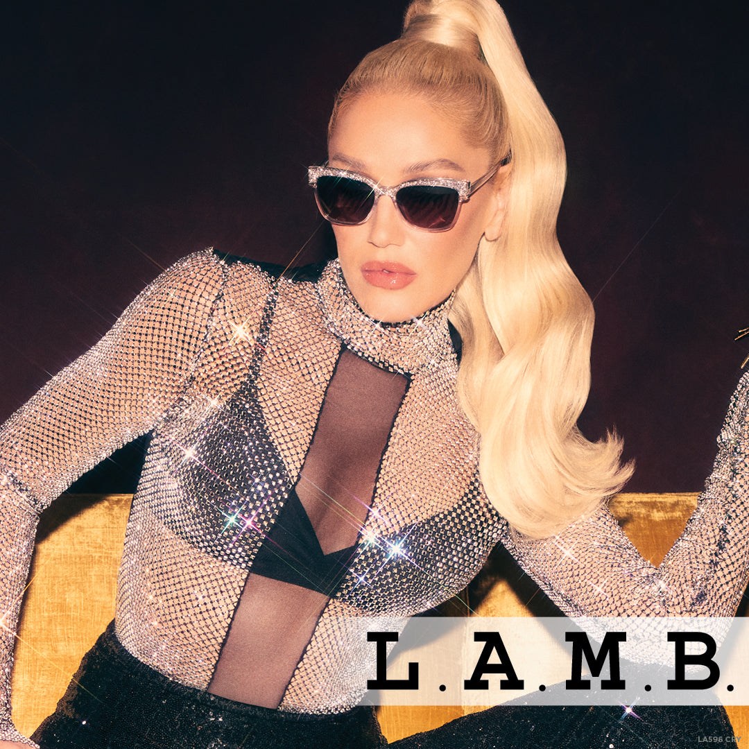 Woman wearing L.A.M.B. LA596 CRY Sunglasses with crystal acetate frame and silver accents, dressed in sparkling mesh top.