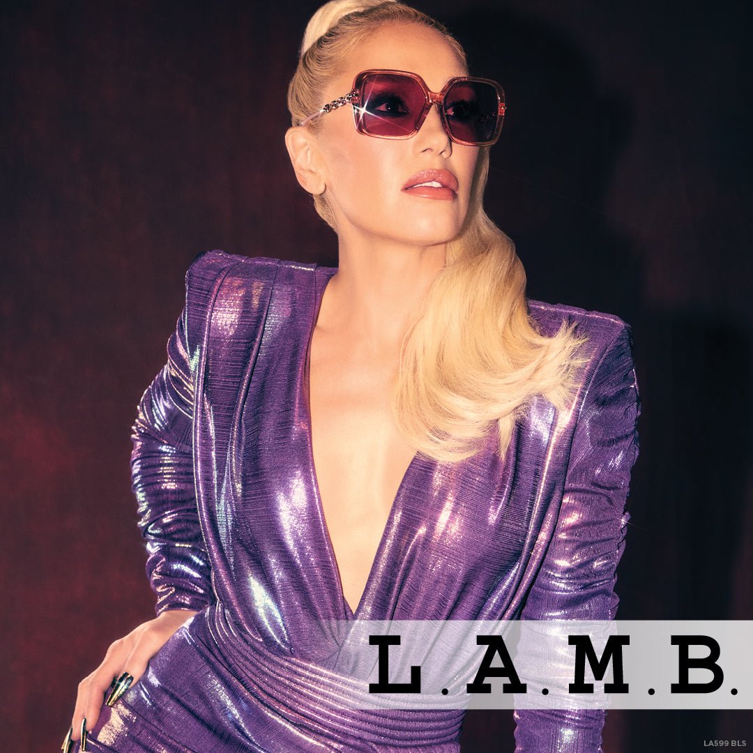 L.A.M.B. LA599 BLS Sunglasses with oversized blush crystal frames and rose gold chain detail, featuring pink-tinted UV400 lenses for stylish sun protection.