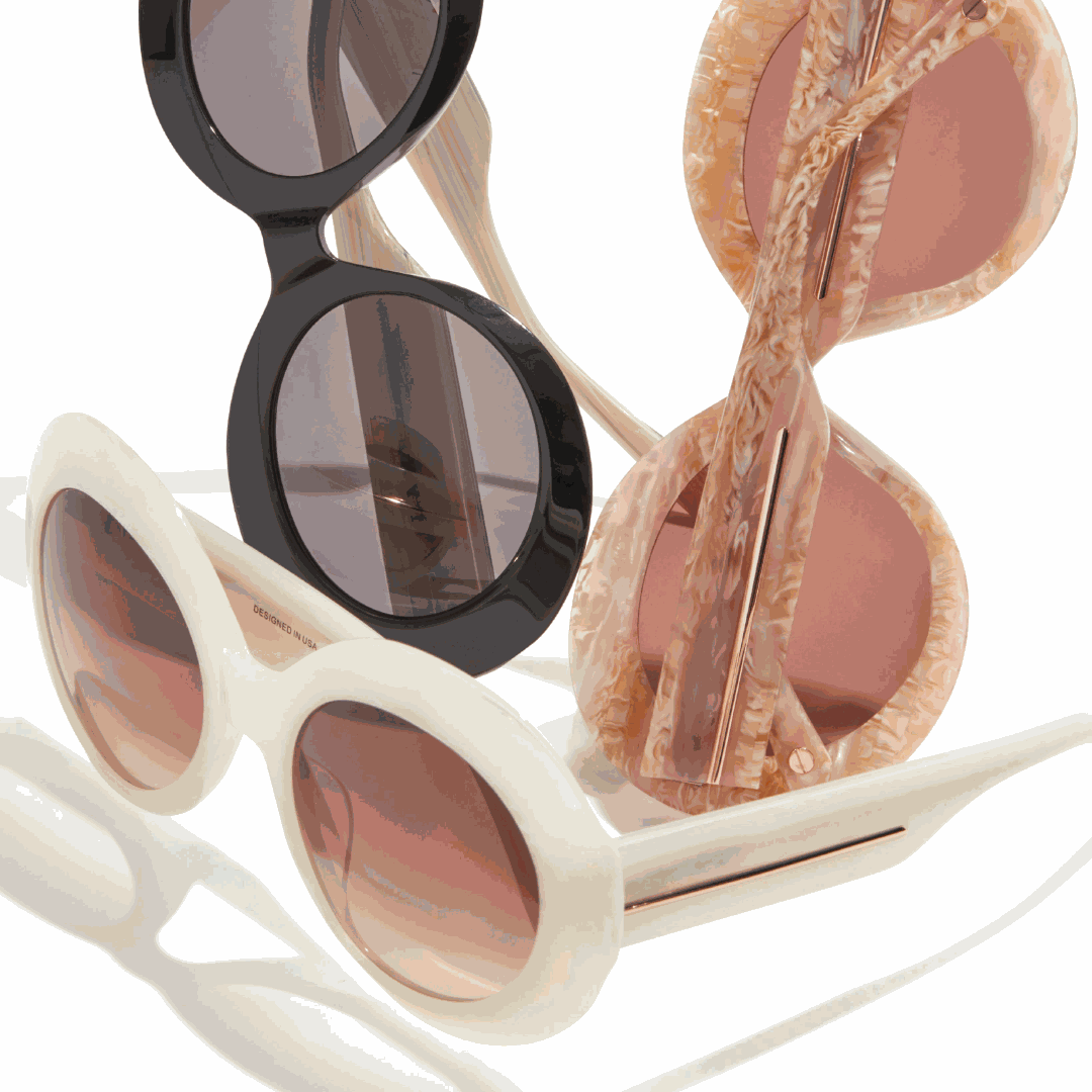 Three pairs of L.A.M.B. LA595 BON Sunglasses in black, white, and bone marble acetate with oversized oval frames and gold detailing.