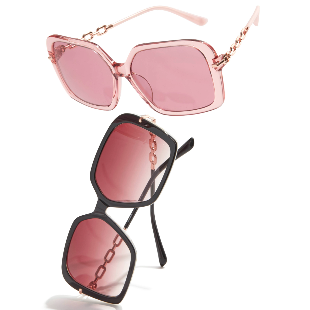 Two pairs of L.A.M.B. LA599 BLS Sunglasses with oversized square frames, one in blush crystal acetate with rose gold chain detail and pink-tinted lenses, the other in black with similar rose gold chain accents.