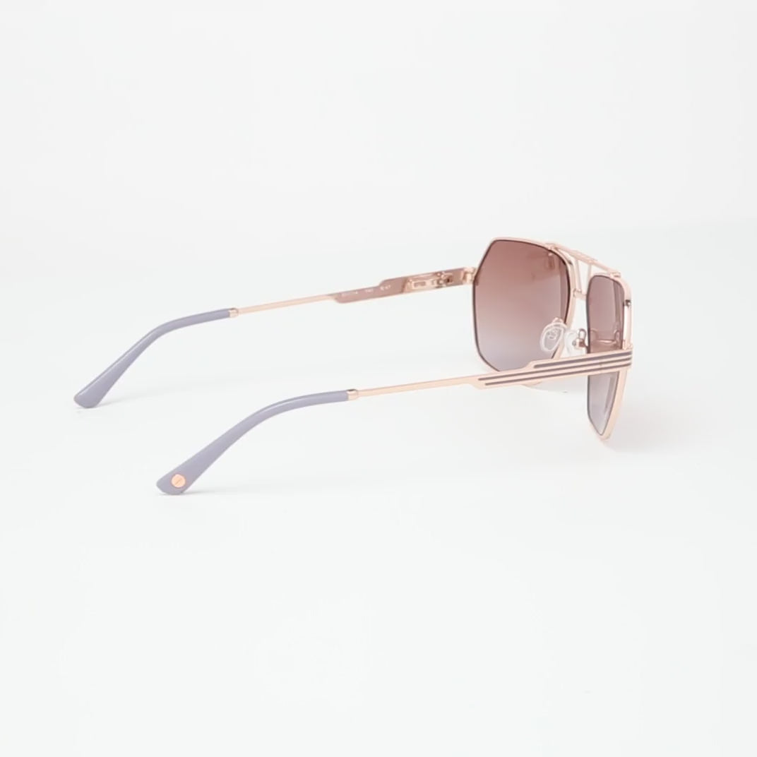 L.A.M.B. LA577 RGD sunglasses with a geometric aviator rose gold metal frame, gradient brown lenses, signature cutout bridge design, and sleek striped temples with grey temple tips. 360 view.