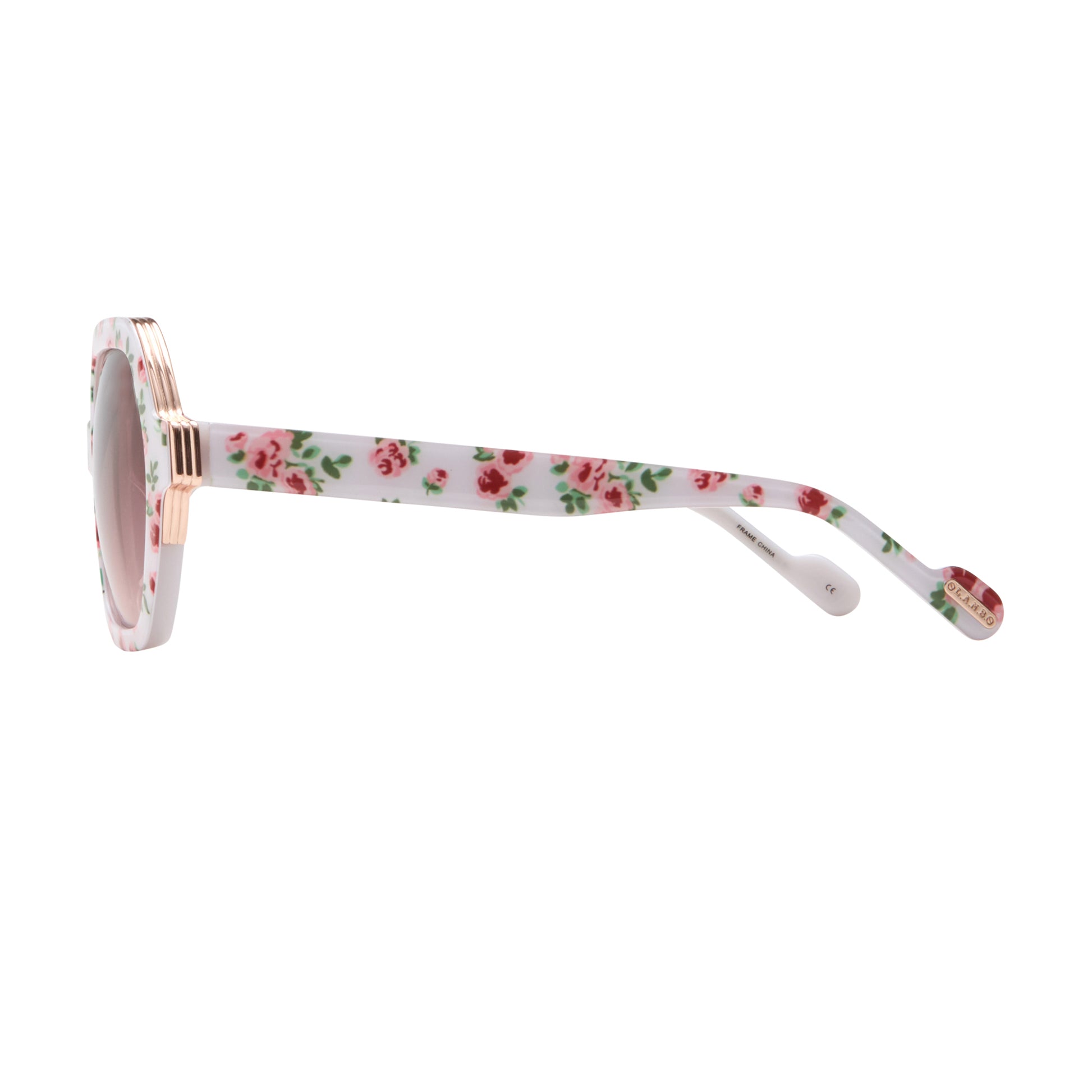Side profile of L.A.M.B. LA601 WHT Sunglasses showing white floral acetate arms, gold accent at hinge, oversized frame design, burgundy gradient lenses.