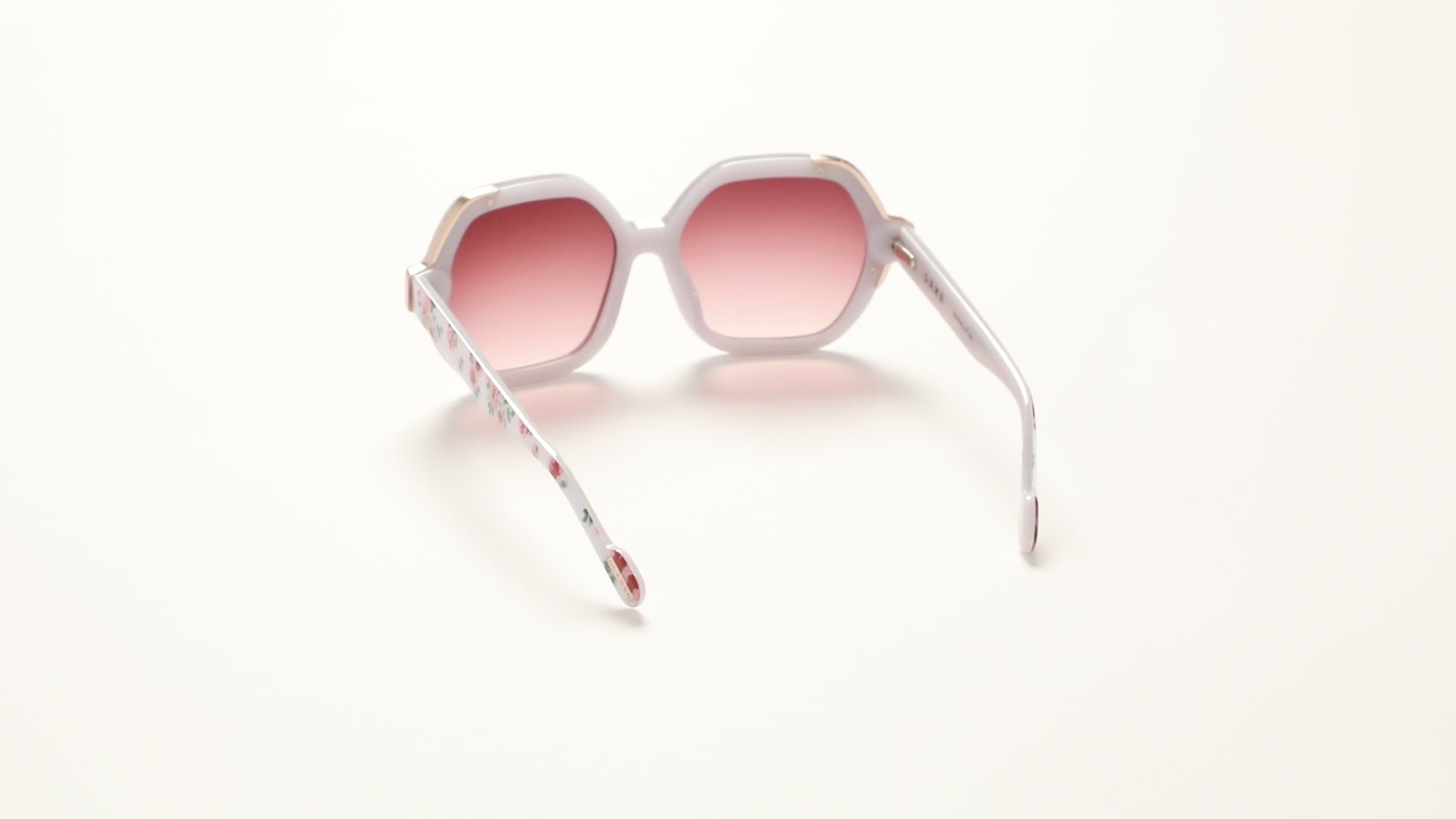 360-degree view of L.A.M.B. LA601 WHT Sunglasses by Gwen Stefani, oversized white floral acetate frame with elegant gold front detail, burgundy gradient lenses, 100% UVA+UVB protection.