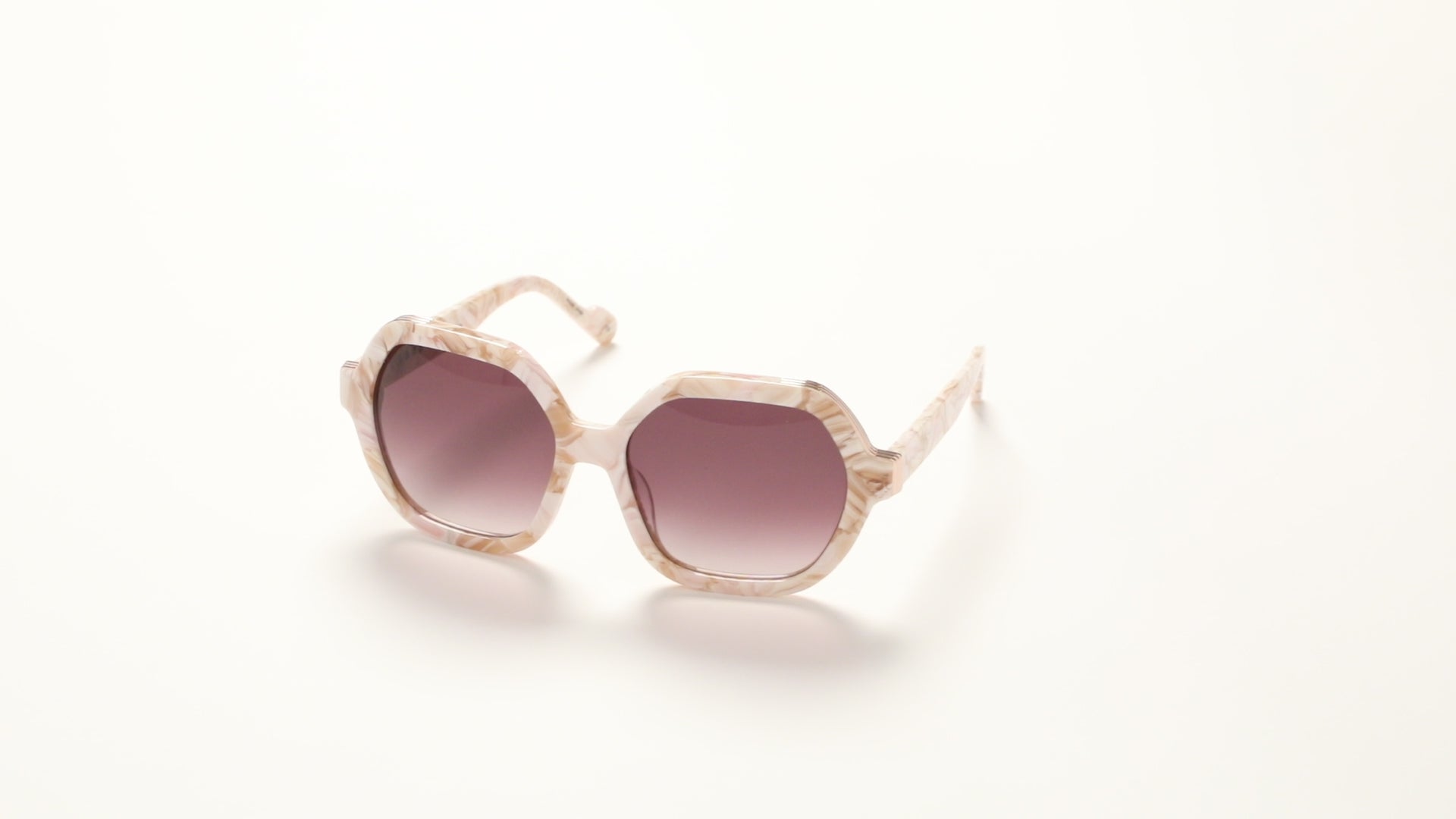360-degree view of L.A.M.B. LA601 BLS Sunglasses in oversized blush marble acetate frame with elegant gold front detail and burgundy gradient lenses, 100% UVA+UVB protection.